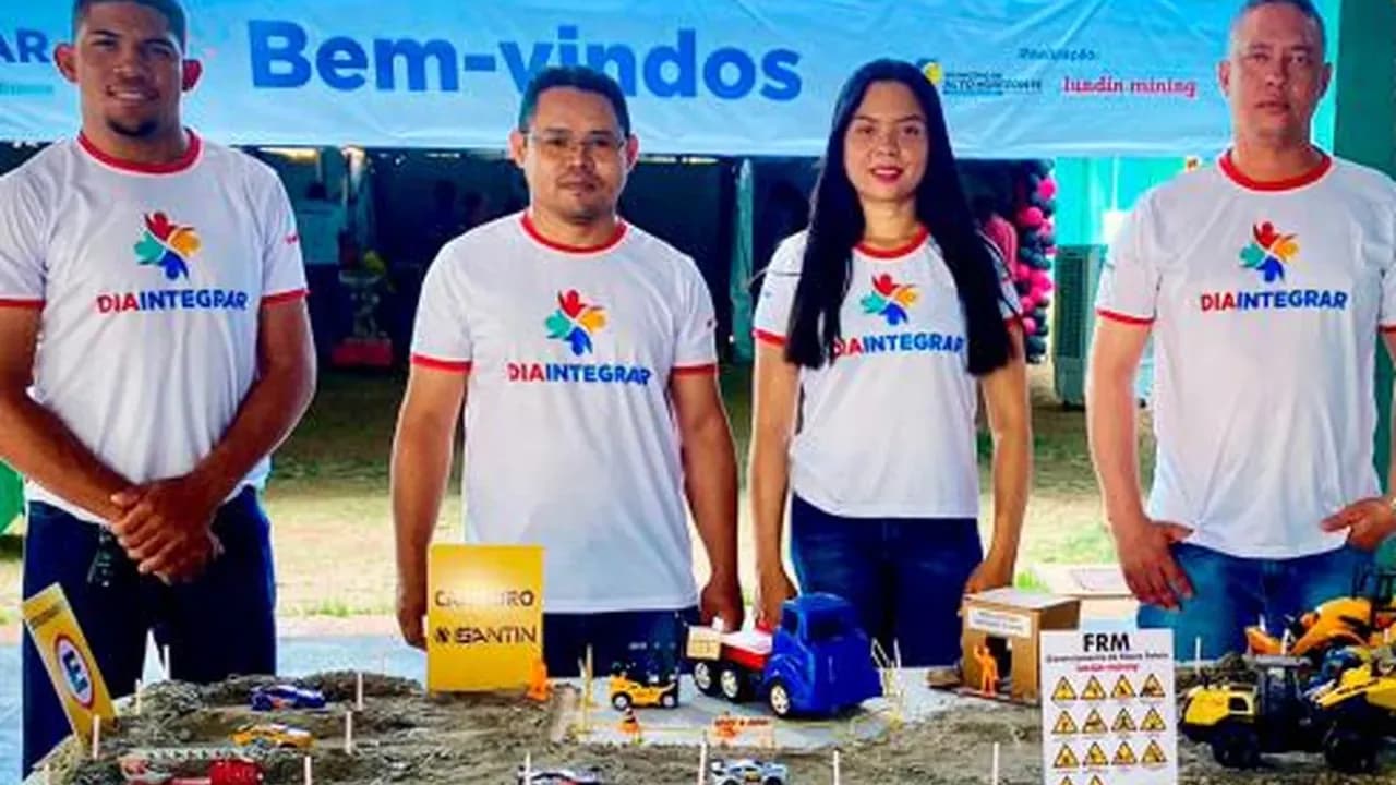 Colaboradores com camisetas do Dia Integrar ao lado de maquete com miniaturas de caminhões e guindastes