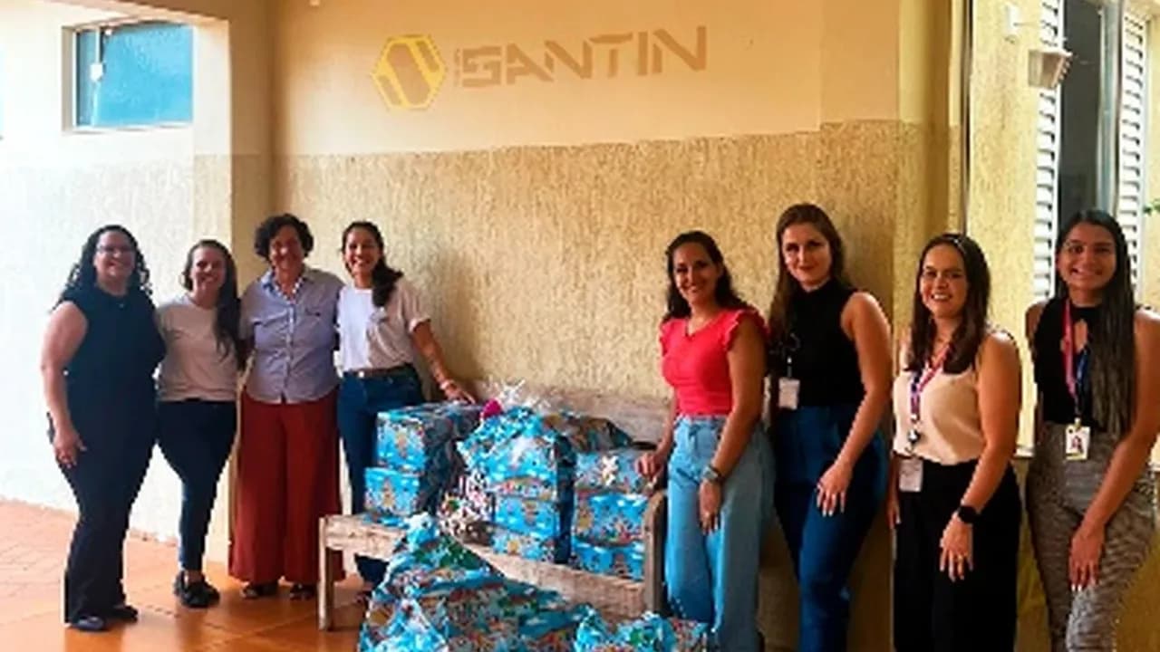 Colaboradoras da Santin ao lado de presentes de Natal embrulhados para doação