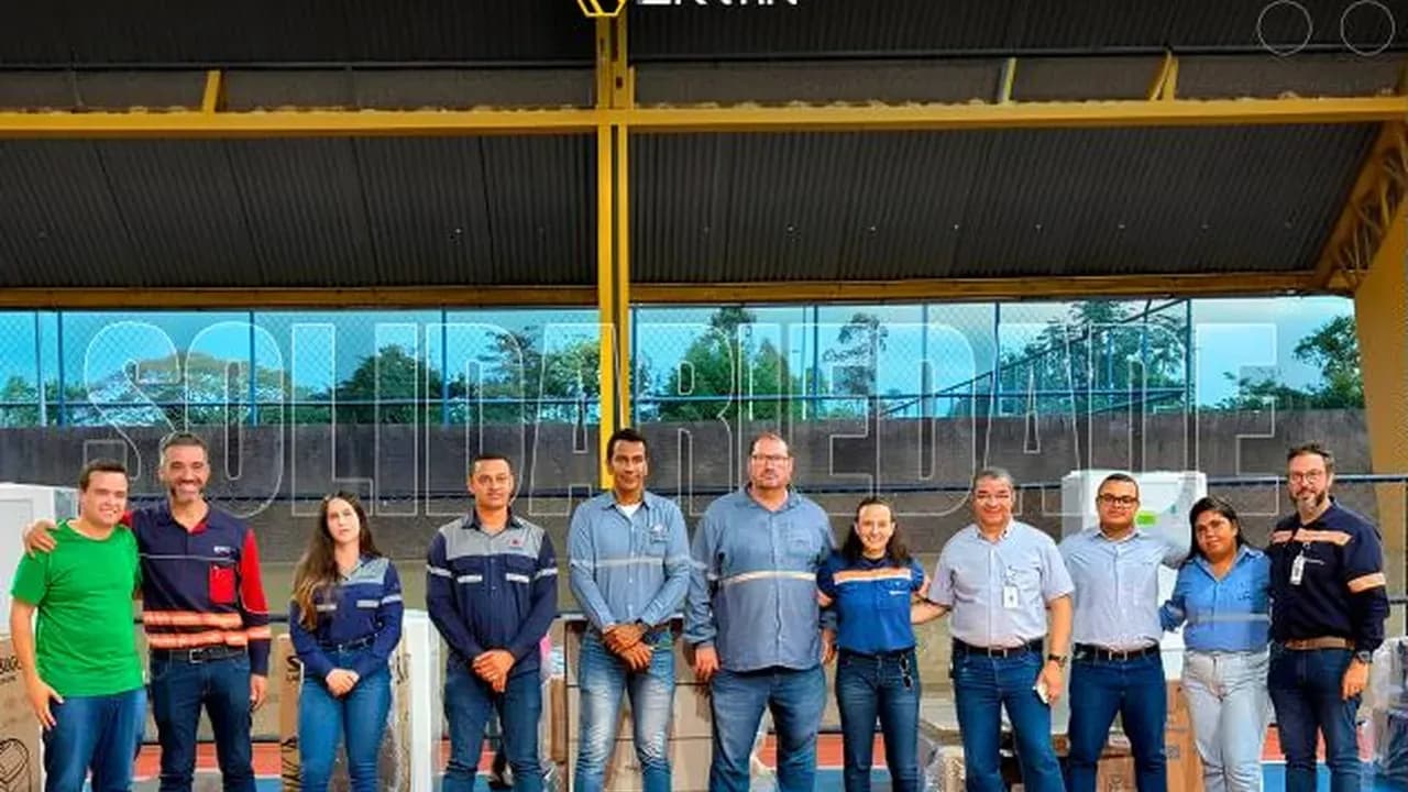 Colaboradores da Santin em quadra esportiva ao lado de eletrodomésticos doados a famílias atingidas pelas chuvas