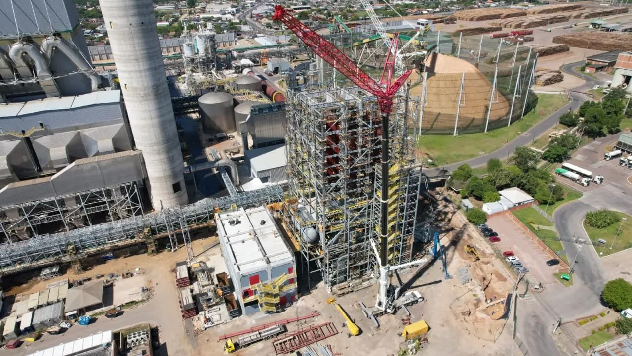 Vista aérea da caldeira de biomassa em montagem na CMPC, com guindaste de treliça vermelho ao lado da estrutura e o parque fabril ao fundo