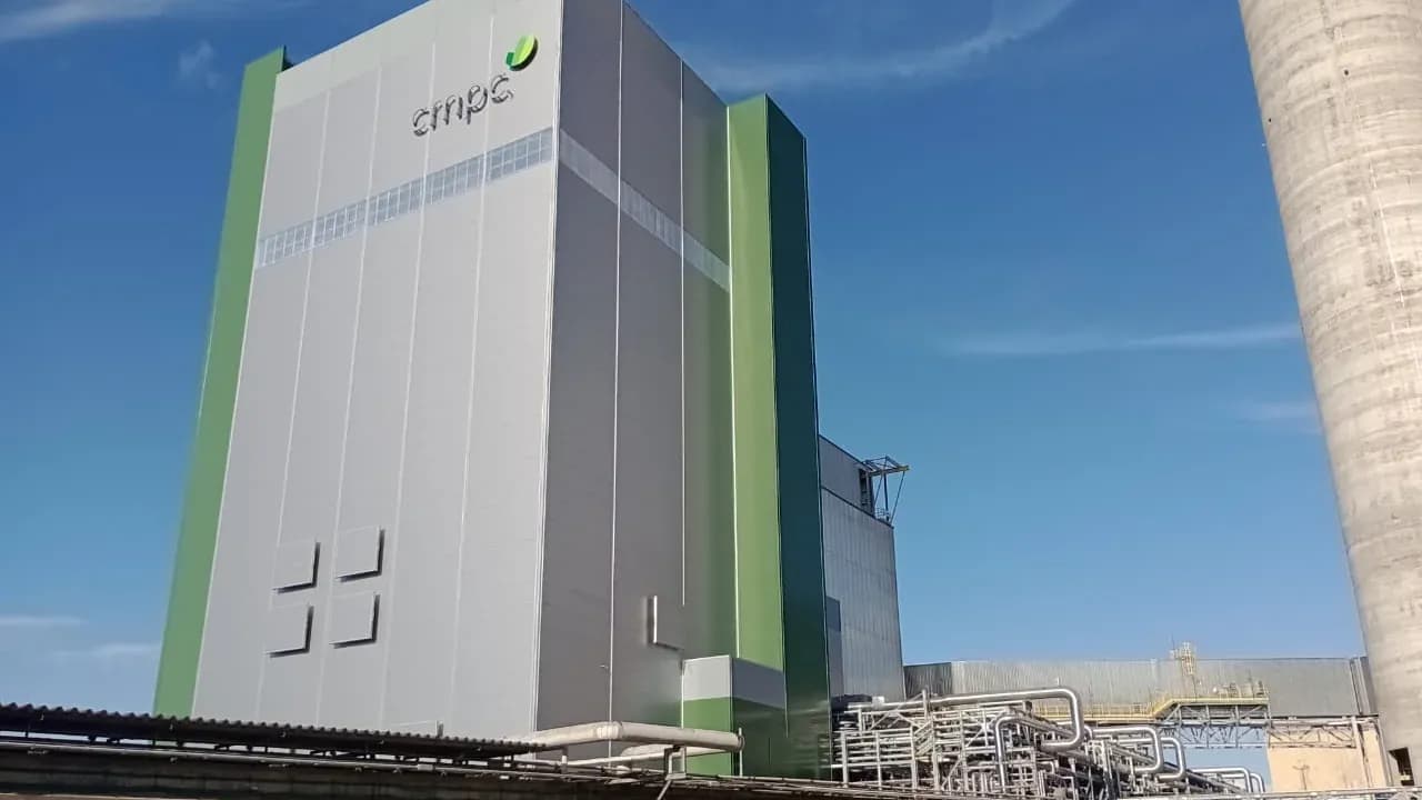 Fachada da caldeira da CMPC revestida em cinza e verde com o logotipo cmpc, sob céu azul