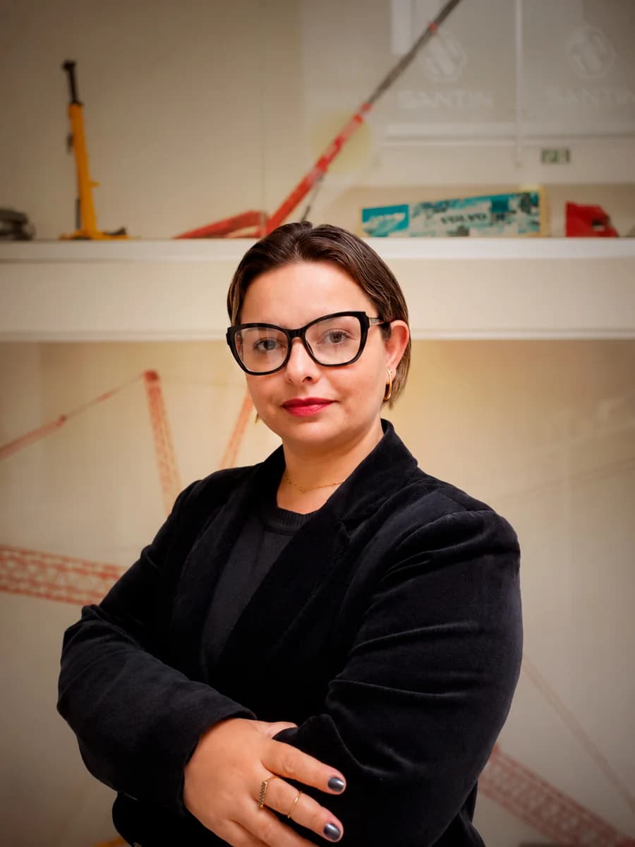 Adriana Aparecida Ferreira, de braços cruzados, diante do painel com guindastes da Santin