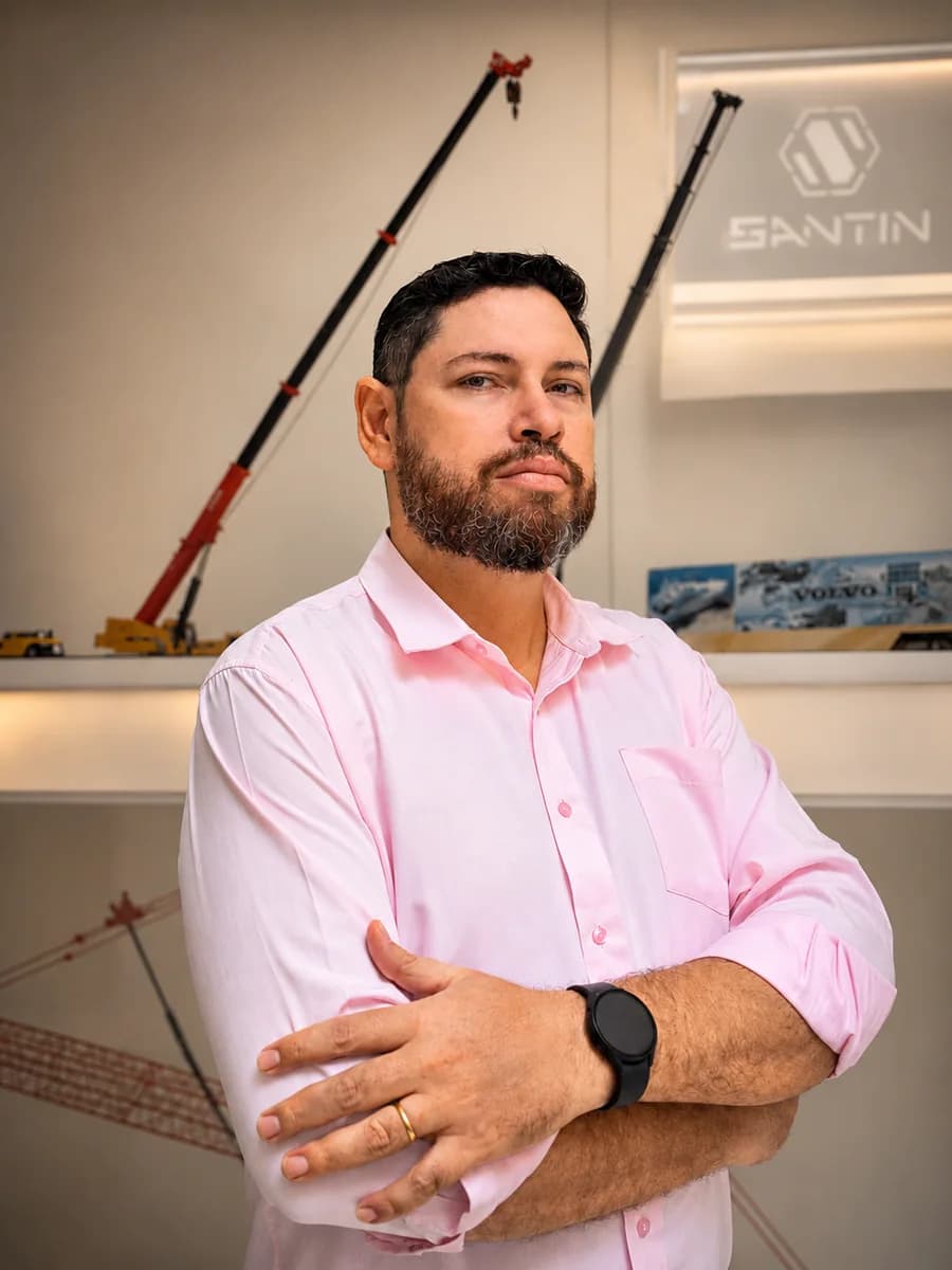 Ulisses Romão, de braços cruzados, diante do painel com guindastes da Santin