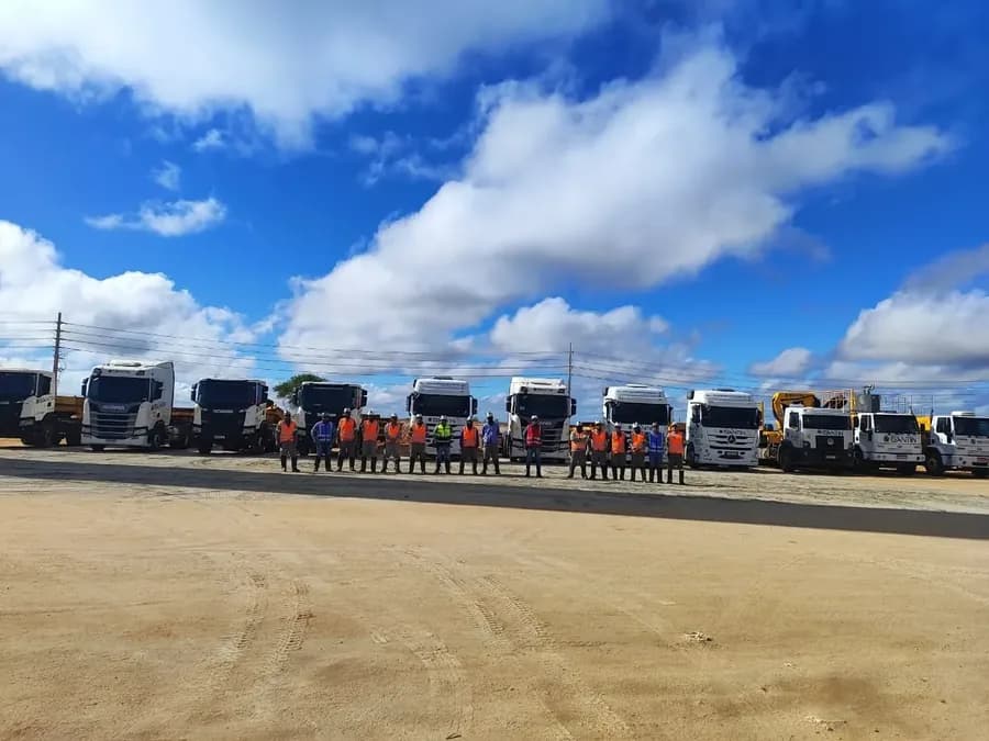 Equipe do Grupo Santin com EPI completo diante da frota de caminhões e guindastes